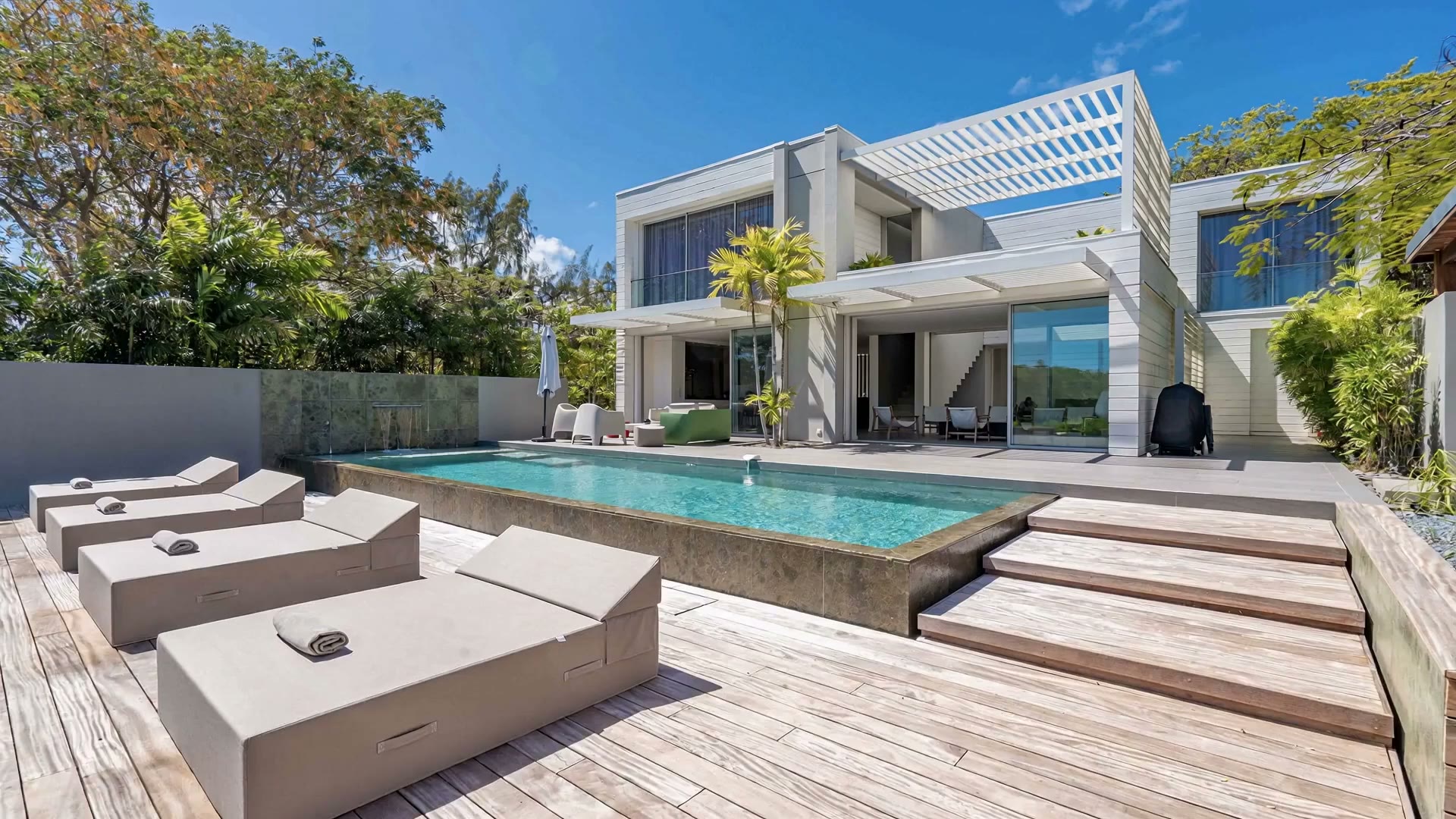 La terrasse en bois et la piscine devant la villa